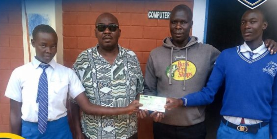 A bursary cheque handed over to students at a school computer laboratory